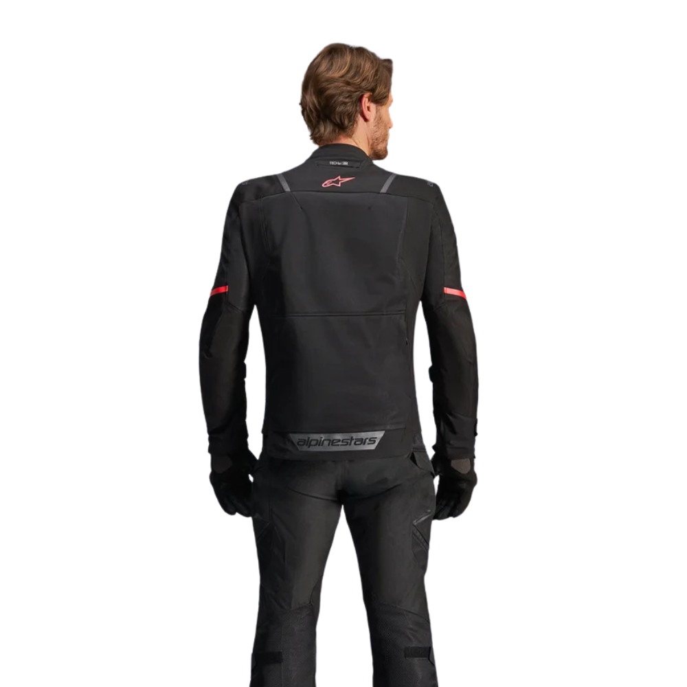A man viewed from the back wearing a black Alpinestars motorcycle jacket and matching pants against a plain white background.