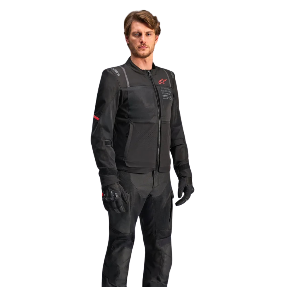 A man modeling a black Alpinestars motorcycle jacket and matching pants with black gloves, shown against a plain white background.