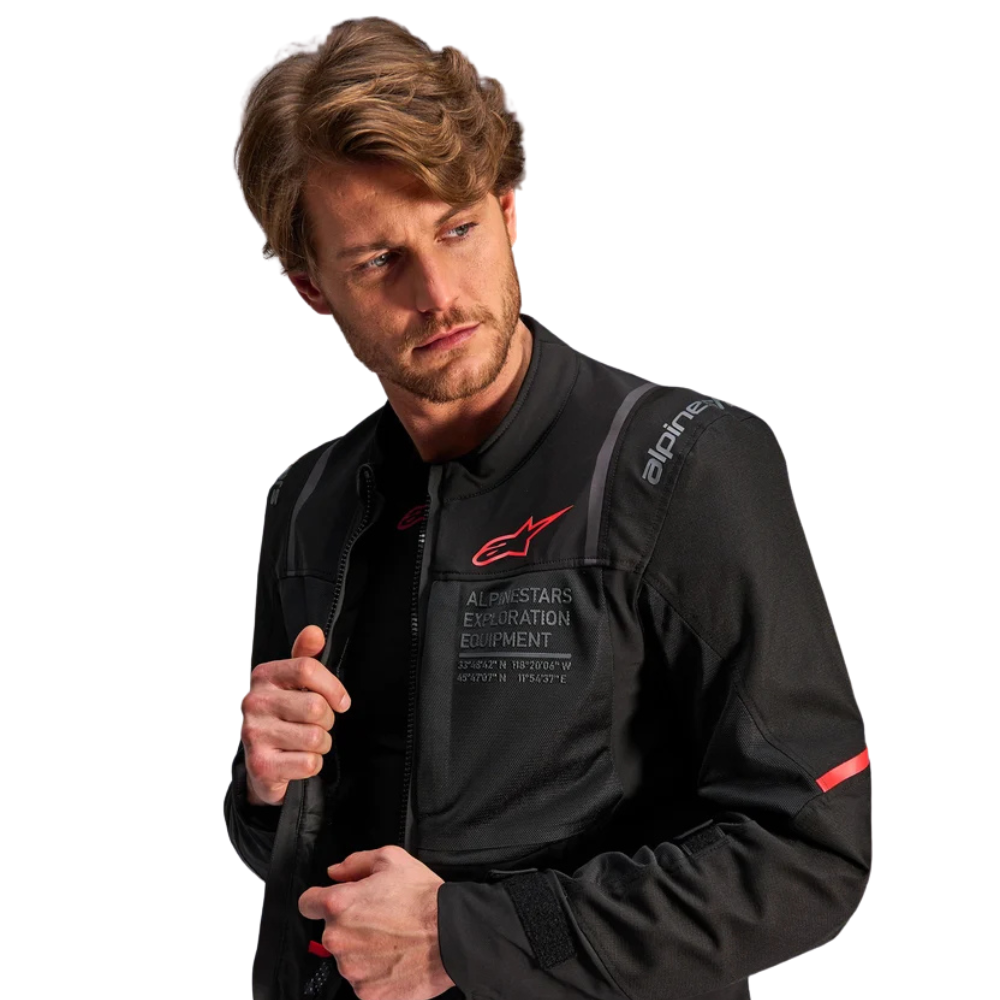 A man wearing a black Alpinestars motorcycle jacket with red and white logo details, photographed against a solid white background.