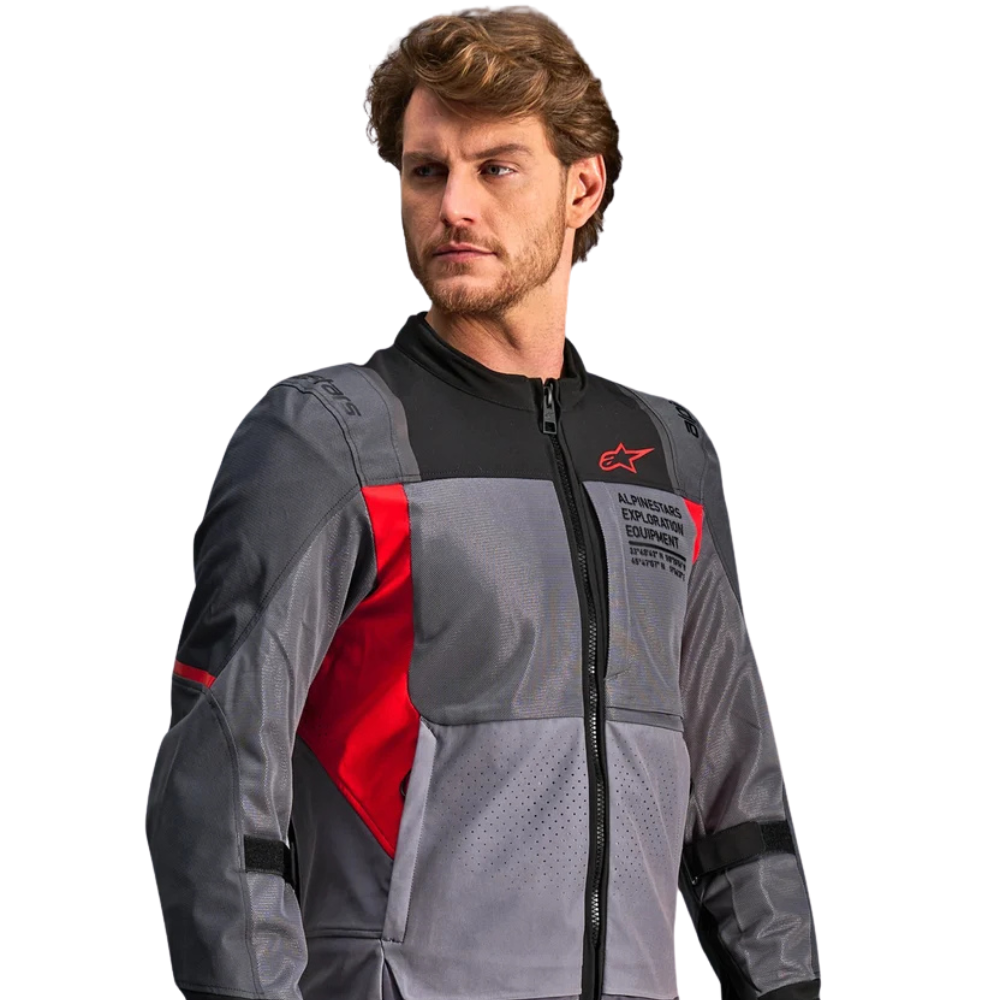 A man wearing a gray and black Alpinestars motorcycle jacket with red accents, shown from the chest up against a plain white background.