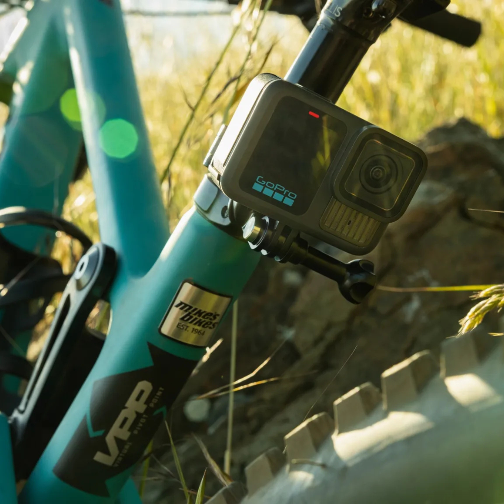 GoPro camera mounted on a teal bicycle with a blurred natural background