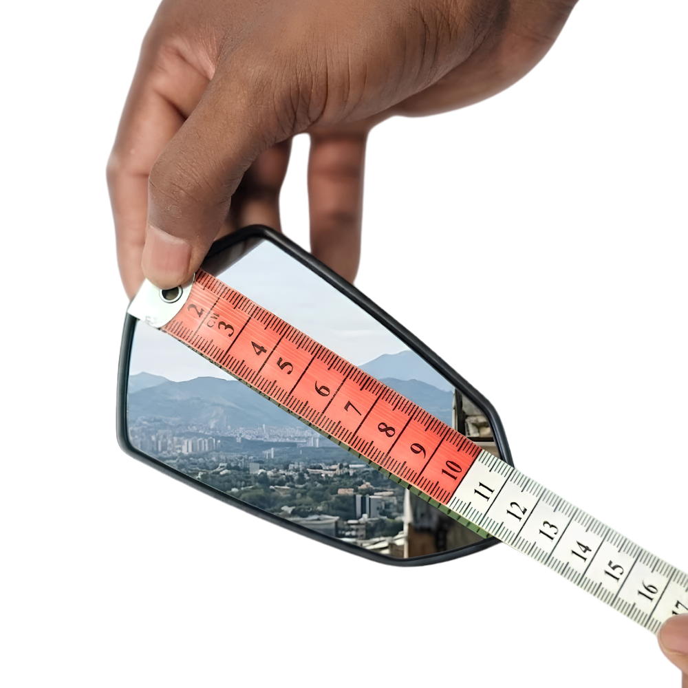 A hand holds a small rectangular mirror against a white background while a measuring tape is placed diagonally across it to show the product's dimensions.