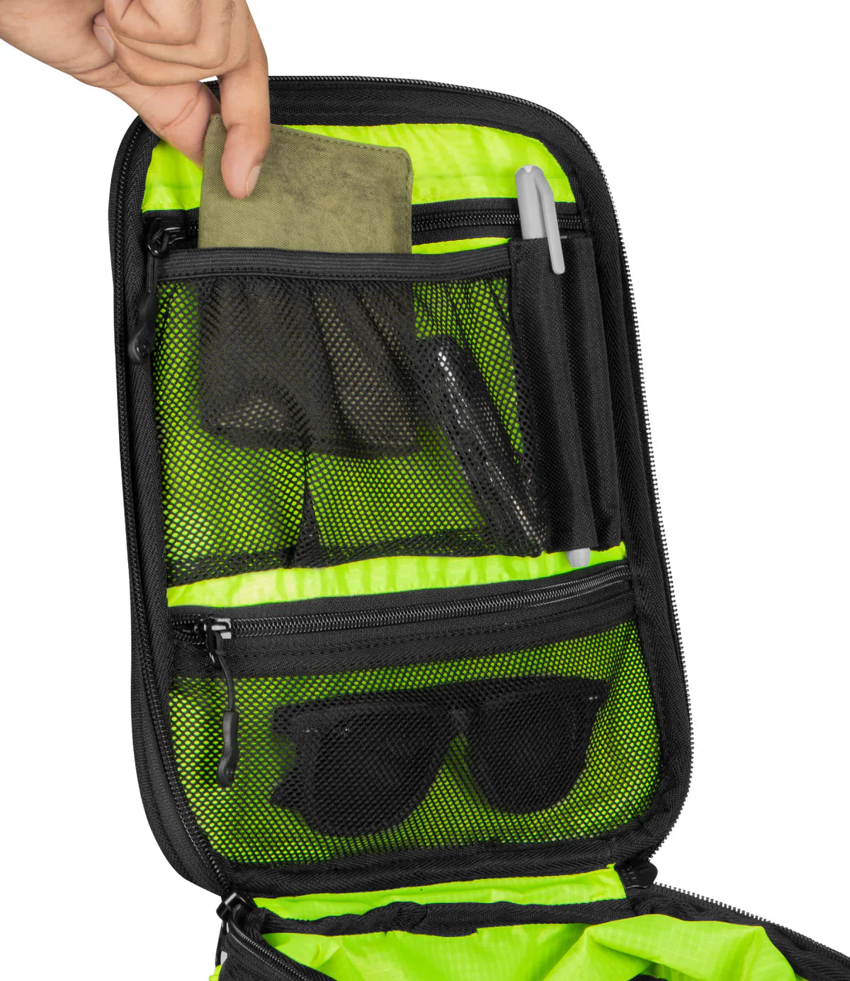 Green and black travel bag with sunglasses and a pen, held open by a hand.